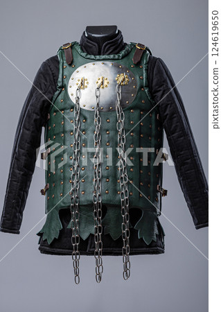 Green Brigandine Armor with Chains. Medieval torso protection featuring metal plates and hanging chains. 124619650