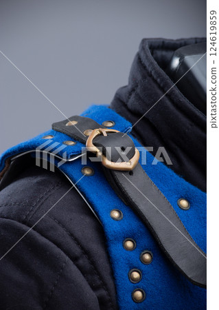 Close-Up of Bright Blue Brigandine Armor Details. This image provides a detailed close-up of the bright blue brigandine armor, showcasing the brass-colored studs, black leather straps with silver Close-Up of Bright Blue Brigandine Armor Details. This image provides a detailed close-up of the bright blue brigandine armor, showcasing the brass-colored studs, black leather straps with silver 124619859