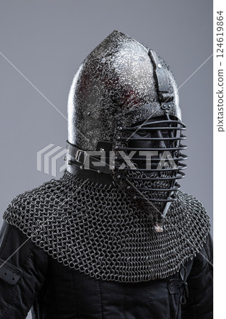 Dark Helmet with Ribbed Faceplate and Chainmail. This image shows a dark, possibly blackened steel, helmet with a pointed top and a distinctive faceplate featuring a series of horizontal ribs. A 124619864