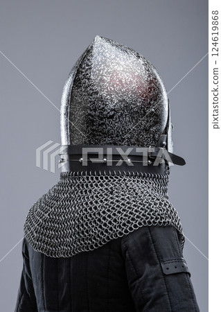 Dark Metal Helmet with Pointed Top and Faceplate. This image shows a dark metal helmet with a pointed top and a faceplate that covers the lower part of the face, featuring several horizontal slits for Dark Metal Helmet with Pointed Top and Faceplate. This image shows a dark metal helmet with a pointed top and a faceplate that covers the lower part of the face, featuring several horizontal slits for 124619868