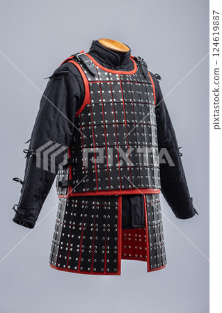 Black Leather Samurai Armor with Red Trim. Traditional Japanese warrior garment featuring layered leather plates and vibrant red accents. 124619887