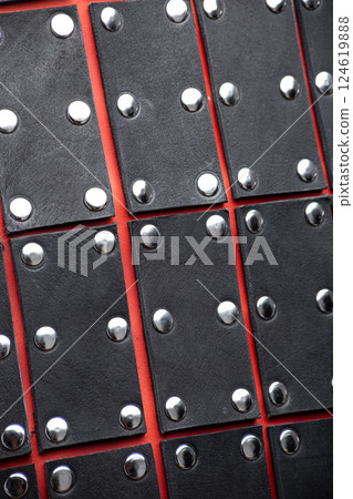 Close-Up Detail of Black Leather Samurai Armor Plates. Detailed texture of layered leather pieces with metal stud accents, forming a traditional Japanese defense. 124619888