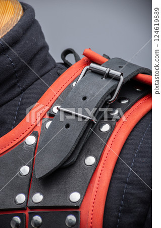 Close-Up Detail of Black Leather Samurai Armor. Intricate construction featuring layered leather plates with vibrant red edging and metal studs. 124619889