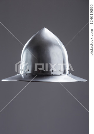 Polished steel medieval infantry kettle hat. Front view of a polished steel medieval kettle hat helmet with pointed dome, wide brim, and rivets on a plain background. Polished steel medieval infantry kettle hat. Front view of a polished steel medieval kettle hat helmet with pointed dome, wide brim, and rivets on a plain background. 124619896