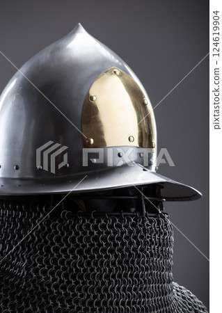 Elegant Medieval Helmet with Gold Accent and Chainmail. Sophisticated head protection featuring a polished finish, golden detail, and attached chainmail. Elegant Medieval Helmet with Gold Accent and Chainmail. Sophisticated head protection featuring a polished finish, golden detail, and attached chainmail. 124619904