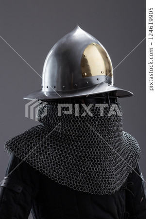 Elegant Medieval Helmet with Gold Accent and Chainmail. Sophisticated head protection featuring a polished finish, golden detail, and attached chainmail. 124619905