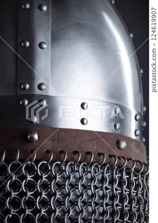 Riveted Metal Helmet with Leather Band and Chainmail. Close-up view of a historical helmet featuring metal plates, a leather strap, and chainmail. Riveted Metal Helmet with Leather Band and Chainmail. Close-up view of a historical helmet featuring metal plates, a leather strap, and chainmail. 124619907