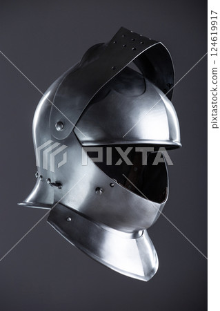 Medieval Knight's Polished Steel Armet Helmet. Detailed close-up of a shiny, historical piece of protective headgear worn by knights in the Middle Ages. Medieval Knight's Polished Steel Armet Helmet. Detailed close-up of a shiny, historical piece of protective headgear worn by knights in the Middle Ages. 124619917