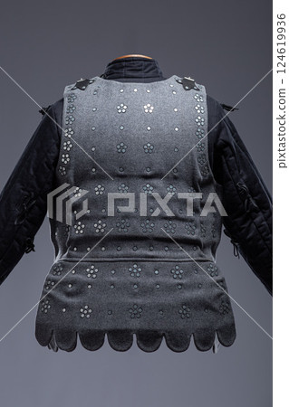 Gray Medieval Brigandine Armor with Leather Straps. This gray brigandine features overlapping metal plates riveted to a fabric base, secured with leather straps. Gray Medieval Brigandine Armor with Leather Straps. This gray brigandine features overlapping metal plates riveted to a fabric base, secured with leather straps. 124619936