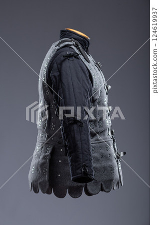 Gray Medieval Brigandine Armor with Leather Straps. This gray brigandine features overlapping metal plates riveted to a fabric base, secured with leather straps. Gray Medieval Brigandine Armor with Leather Straps. This gray brigandine features overlapping metal plates riveted to a fabric base, secured with leather straps. 124619937