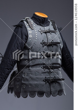 Gray Medieval Brigandine Armor with Leather Straps. This gray brigandine features overlapping metal plates riveted to a fabric base, secured with leather straps. Gray Medieval Brigandine Armor with Leather Straps. This gray brigandine features overlapping metal plates riveted to a fabric base, secured with leather straps. 124619938