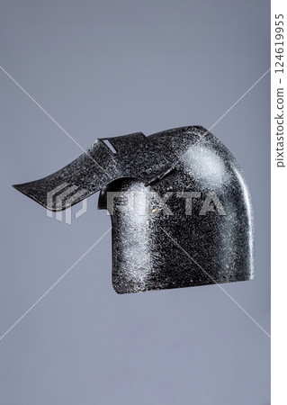 Darkened Steel Medieval Helmet Cheek Piece. Side view of battle-worn head protection detail. 124619955