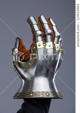 Silver Hourglass Gauntlets with Brass Details. This image shows a close-up of a pair of shiny silver hourglass gauntlets, featuring articulated fingers and brass accents along the edges and rivets. 124619965