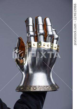 Silver Hourglass Gauntlets with Brass Details. This image shows a close-up of a pair of shiny silver hourglass gauntlets, featuring articulated fingers and brass accents along the edges and rivets. Silver Hourglass Gauntlets with Brass Details. This image shows a close-up of a pair of shiny silver hourglass gauntlets, featuring articulated fingers and brass accents along the edges and rivets. 124619966