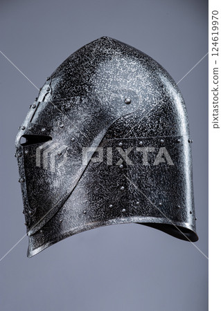 Closed Medieval Knight's Helmet with Small Perforations. This image shows a closed medieval knight's helmet, likely made of steel, with a pointed top and small perforations for ventilation and vision. 124619970