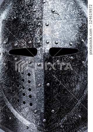Closed Medieval Knight's Helmet with Small Perforations. This image shows a closed medieval knight's helmet, likely made of steel, with a pointed top and small perforations for ventilation and vision. 124619972