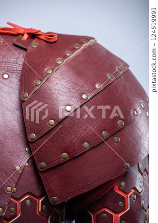 Close-up of Brown Leather Fantasy Shoulder Armor. Detailed view of the shoulder piece with rivets and red lacing. Close-up of Brown Leather Fantasy Shoulder Armor. Detailed view of the shoulder piece with rivets and red lacing. 124619991