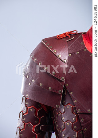 Close-up of Brown Leather Fantasy Shoulder Armor. Detailed view of the shoulder piece with rivets and red lacing. Close-up of Brown Leather Fantasy Shoulder Armor. Detailed view of the shoulder piece with rivets and red lacing. 124619992