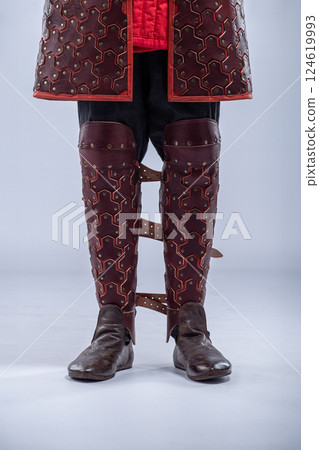 Close-up of Brown Leather Fantasy Leg Armor. Detailed view of the mannequin's leg armor featuring brown leather with red accents and multiple straps. Close-up of Brown Leather Fantasy Leg Armor. Detailed view of the mannequin's leg armor featuring brown leather with red accents and multiple straps. 124619993