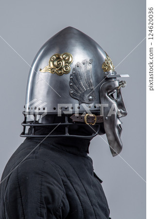 Silver Helmet with Decorative Face Mask. Unique medieval head protection with golden accents Silver Helmet with Decorative Face Mask. Unique medieval head protection with golden accents 124620036