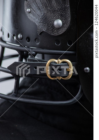Buckled Leather Strap on Black Helmet. Close-up of fastening detail on medieval head protection. 124620044