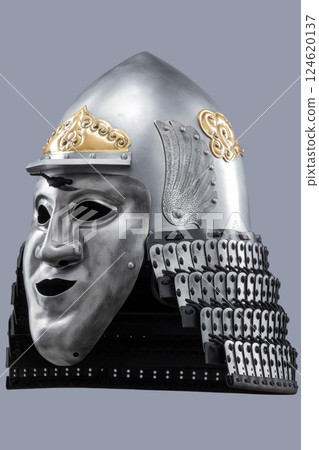 Silver Samurai Helmet with Ornate Gold Details and Fierce Mask. This image showcases a silver samurai helmet with intricate gold decorations on the crown and a detailed face mask with a stern 124620137