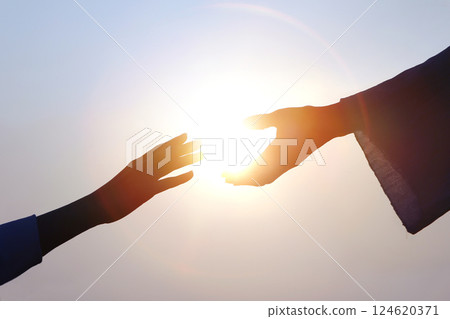 Hand of salvation, Christian hand reaching out to the hand of Jesus Christ, bright sun silhouette 124620371