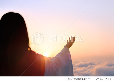 Jesus praying to God with arms raised towards bright light heaven sky, Jesus Christ resurrected from the cross death, Easter background 124620375