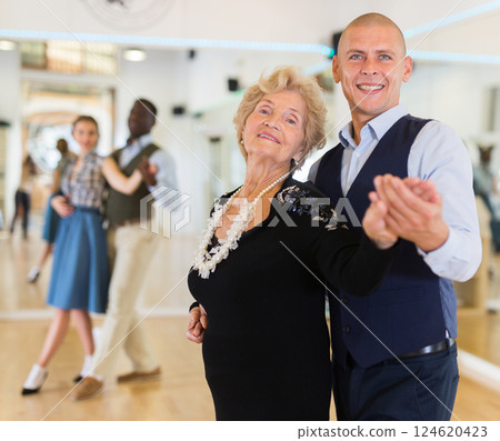 Man and elderly woman performing ballroom dance in dancing room 124620423