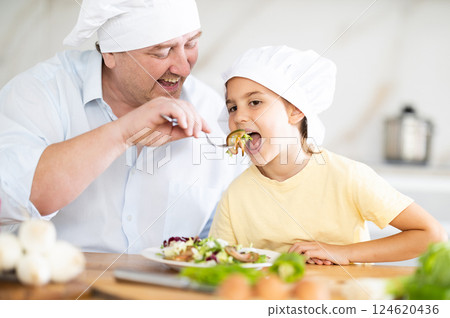 Father gives daughter taste of cooked food 124620436