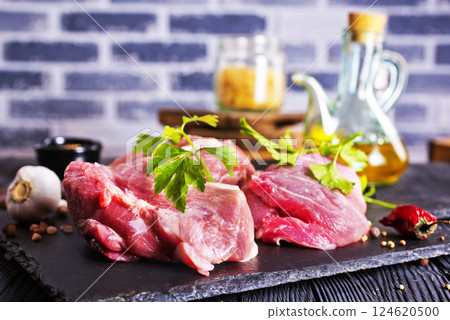 Raw meat with herbs and spices ready for cooking are on wooden table 124620500