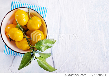 Fresh mandarin oranges fruit or tangerines with leaves on a table Fresh mandarin oranges fruit or tangerines with leaves on a table 124620511
