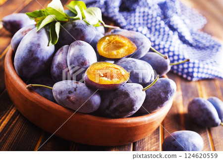 Fresh plums on plate over dark wooden background 124620559