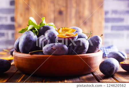 Fresh plums on plate over dark wooden background 124620562