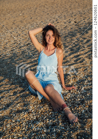 Beautiful slim fashionable woman in white summer dress on the beach by the sea 124620601
