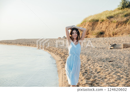 Beautiful slim fashionable woman in white summer dress on the beach by the sea 124620602