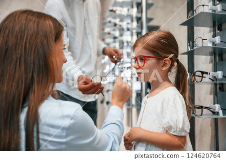 Woman, man and little girl is choosing right glasses for correcting vision Woman, man and little girl is choosing right glasses for correcting vision 124620764