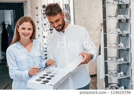 Standing and smiling. Man and woman in the glasses store. Helping to choose product 124620796