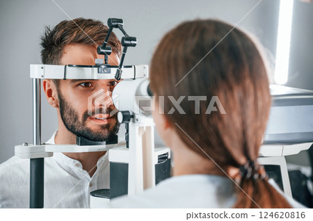 Man's vision checked by female doctor in the clinic by using special optometrist device 124620816
