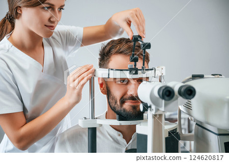 Man's vision checked by female doctor in the clinic by using special optometrist device 124620817