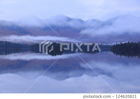 Fog flows over the waterside surrounded by mountains of autumn leaves, creating a world of ink painting 124620821