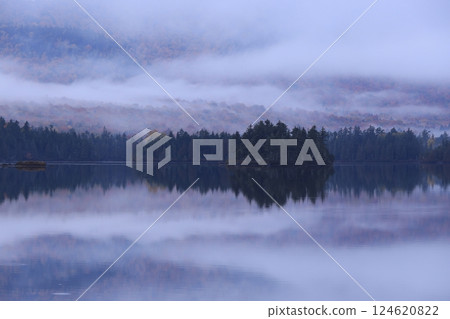 Fog flows over the waterside surrounded by mountains of autumn leaves, creating a world of ink painting 124620822
