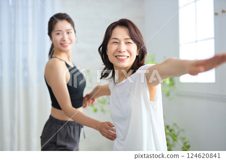 Middle-aged woman receiving lessons from a yoga instructor 124620841