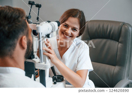 Modern technologies. Man's vision checked by female doctor in the clinic by using special optometrist device Modern technologies. Man's vision checked by female doctor in the clinic by using special optometrist device 124620890