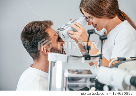 Modern technologies. Man's vision checked by female doctor in the clinic by using special optometrist device Modern technologies. Man's vision checked by female doctor in the clinic by using special optometrist device 124620892