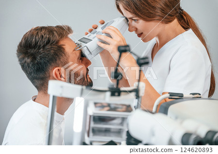 Modern technologies. Man's vision checked by female doctor in the clinic by using special optometrist device Modern technologies. Man's vision checked by female doctor in the clinic by using special optometrist device 124620893