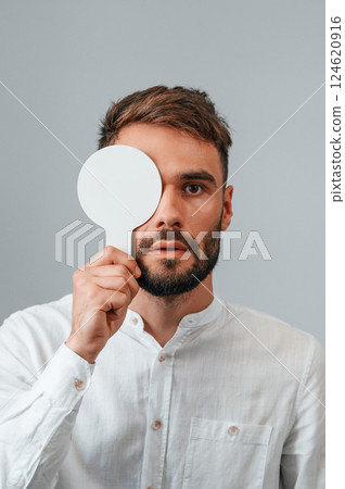 Covering right eye. Man is checking his vision indoors in the clinic Covering right eye. Man is checking his vision indoors in the clinic 124620916