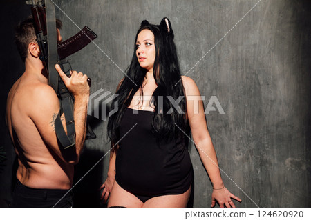 man and woman in black lingerie on dark background with guns 124620920