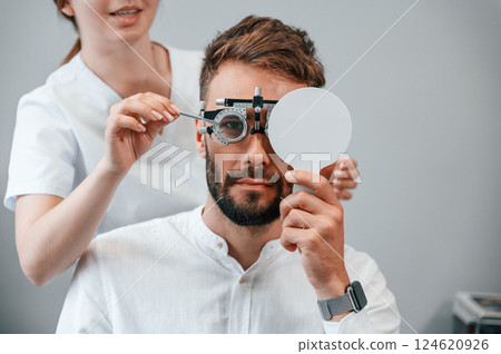 Optometric device. Man's vision checked by female doctor in the clinic Optometric device. Man's vision checked by female doctor in the clinic 124620926