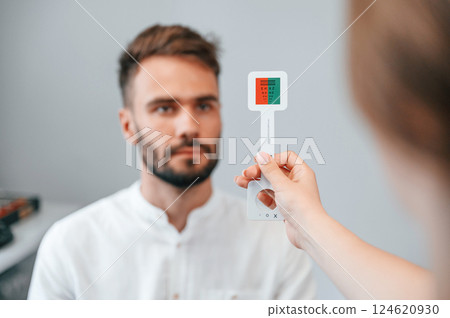 Holding tool. Man's vision checked by female doctor in the clinic by using special optometrist device 124620930